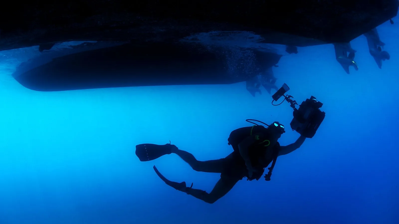 Plongeur en bouteille sous la coque d'un bateau de plongée en eau profonde