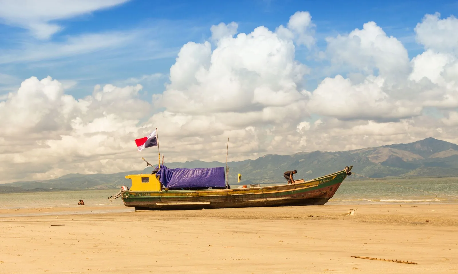 Bateau de pêche panaméen posé sur l'estran de Punta Chame à marée basse, montagnes en arrière-plan