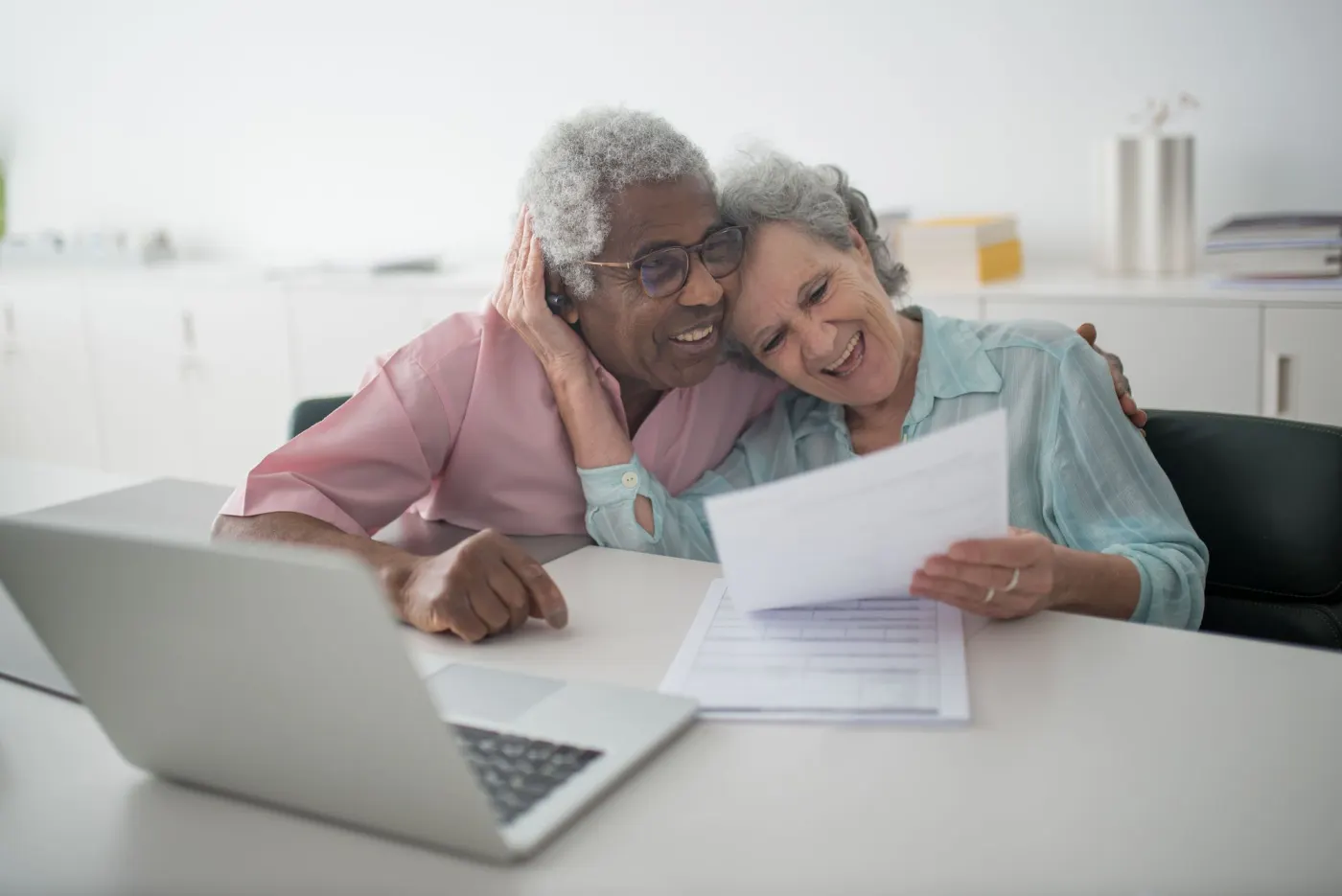 Couple de retraités examinant un relevé de pension devant un ordinateur portable