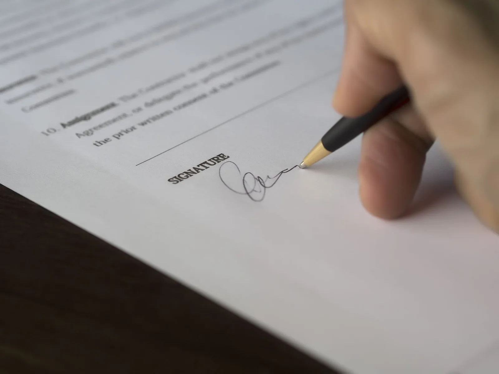 Main signant un document administratif au stylo, en gros plan