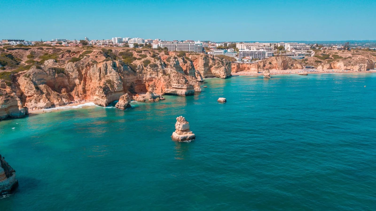 Falaises ocre et eaux turquoise du littoral de l'Algarve au Portugal, avec les immeubles d'une station balnéaire