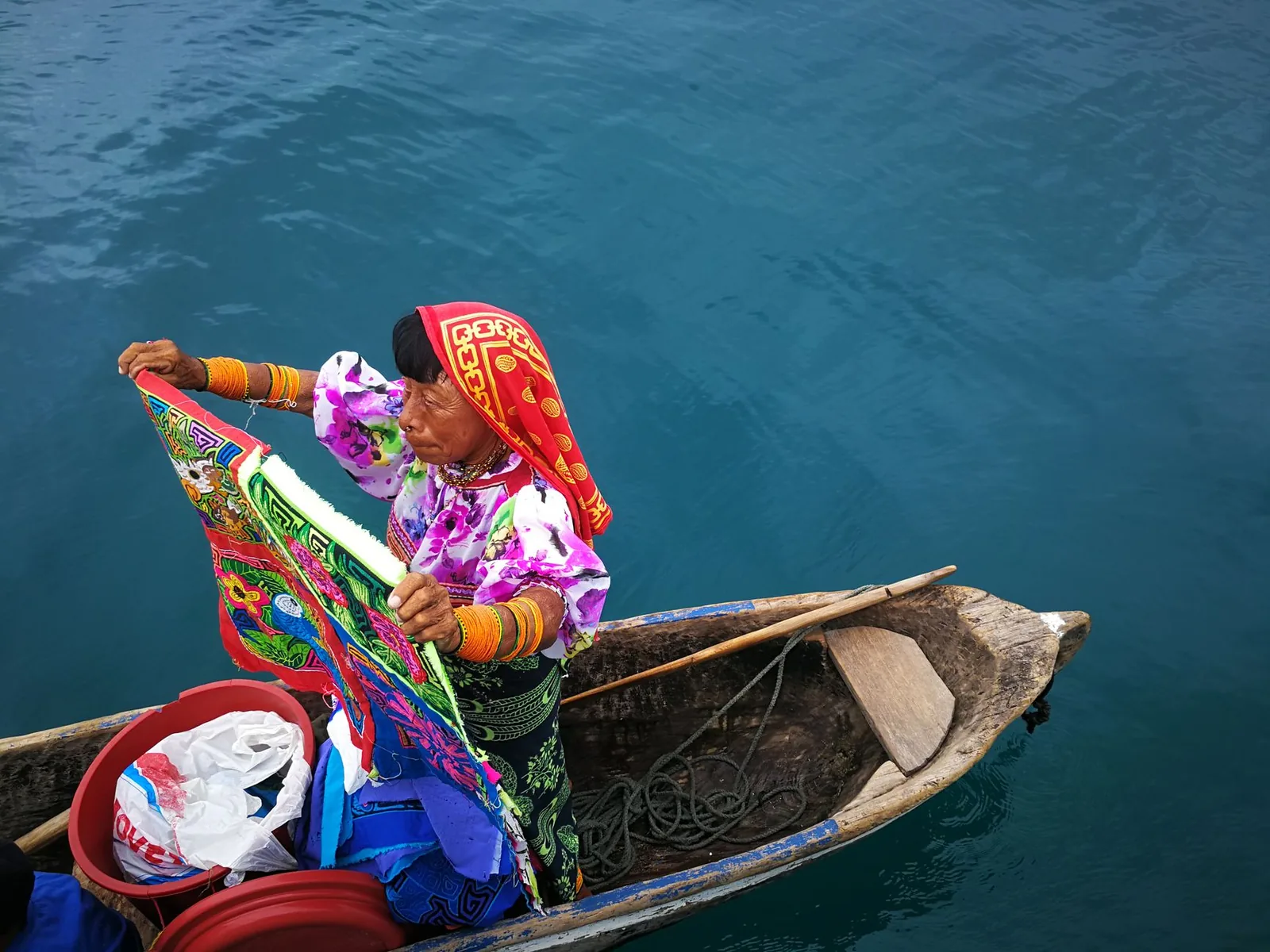 Femme guna présentant des molas depuis un cayuco à Guna Yala, Panama