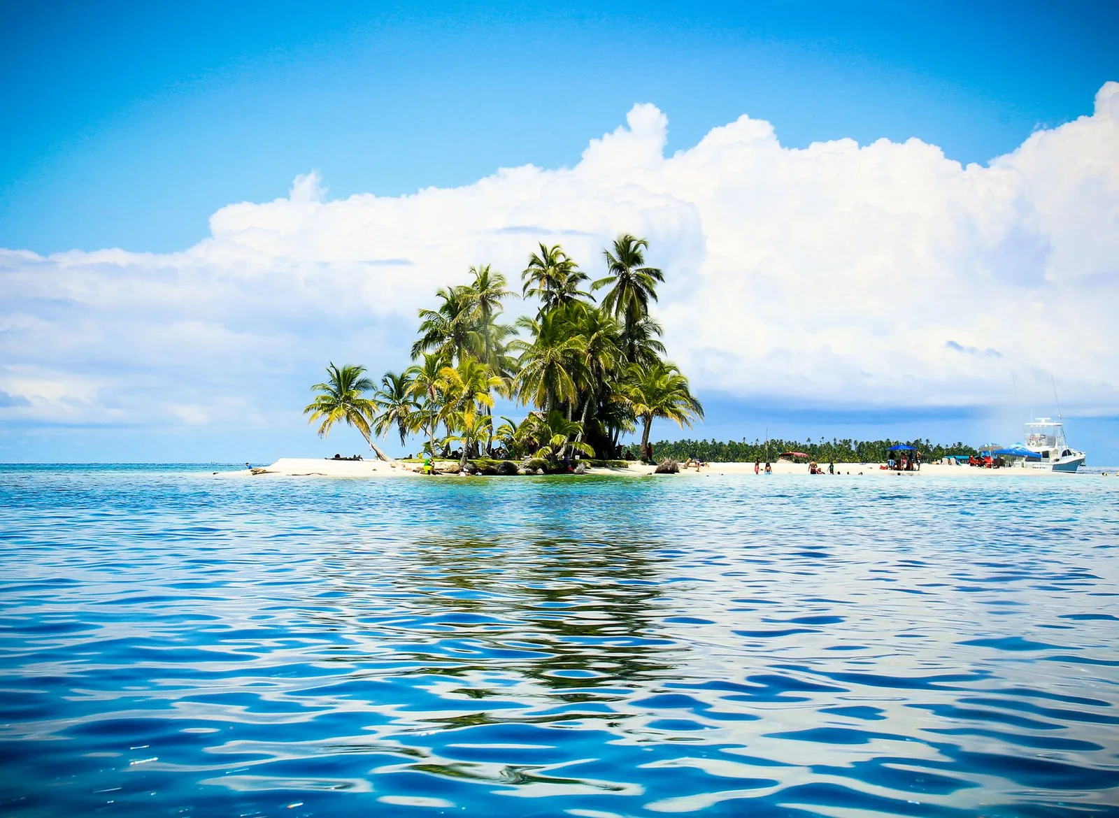 Îlot à cocotiers et lancha de tour au mouillage, archipel San Blas, Panama
