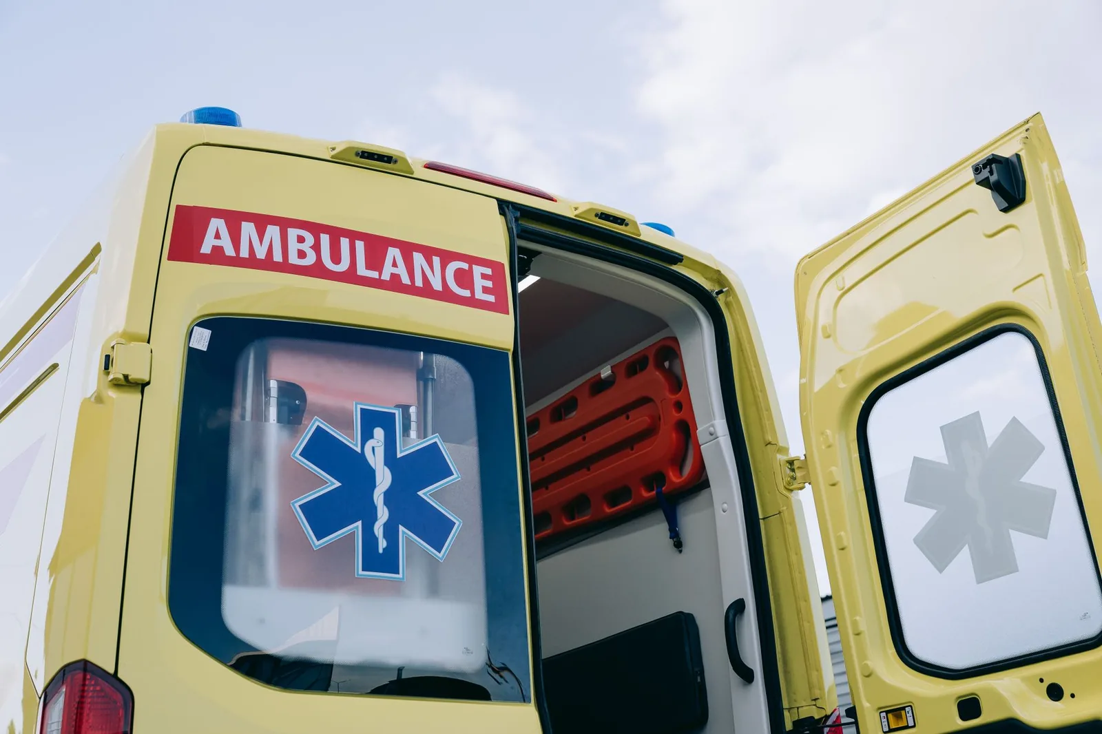 Ambulance portes arrière ouvertes montrant un brancard et l'équipement de transport sanitaire