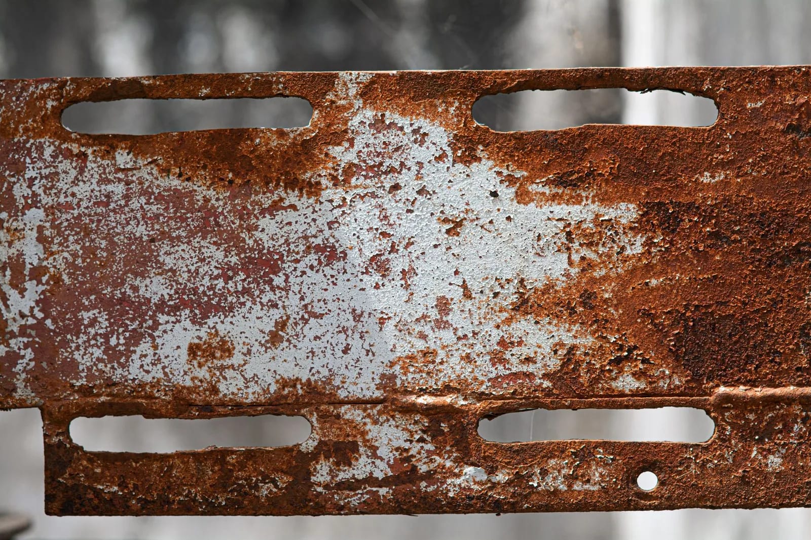 Gros plan sur une plaque métallique rongée par la corrosion, effet typique de l'air marin sur les maisons de bord de mer